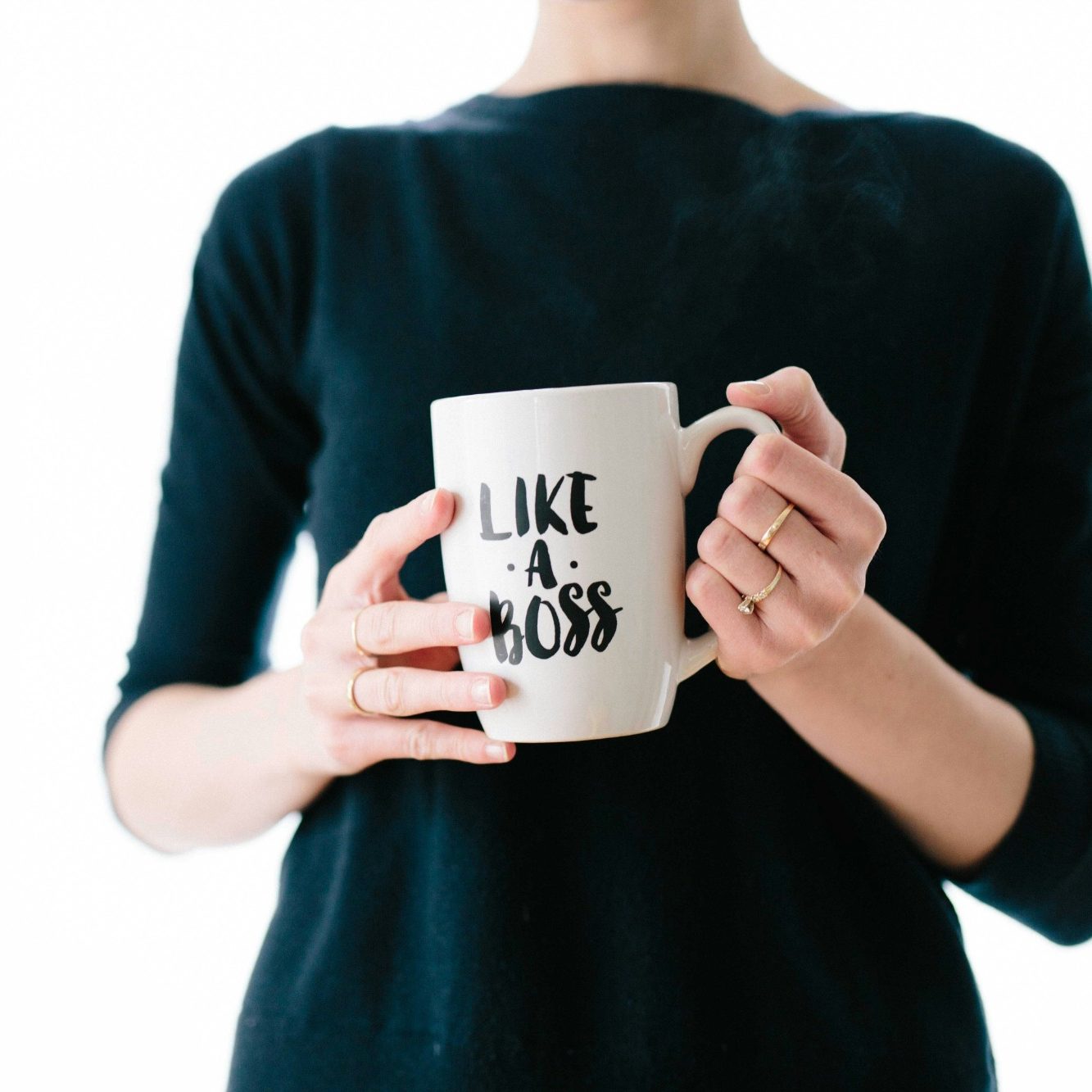 Une personne tient une tasse blanche avec l'inscription "LIKE A BOSS".